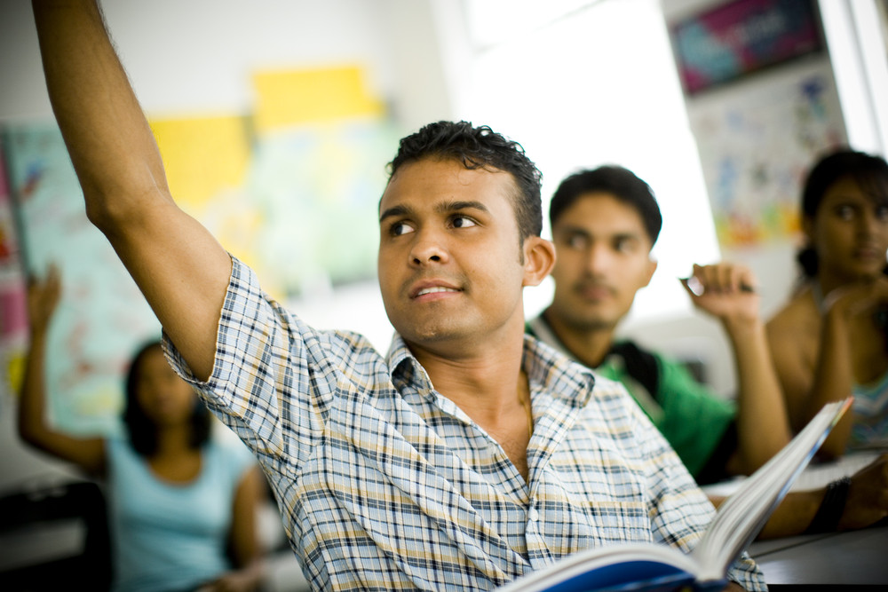 Student raising their hand in class. Student raising their hand in class.